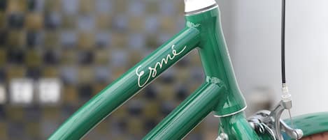 A close-up of a green bicycle frame with the brand name "Esmi" visible.