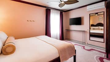 Una habitación de hotel con una cama, un ventilador de techo, un televisor y un espejo de baño.