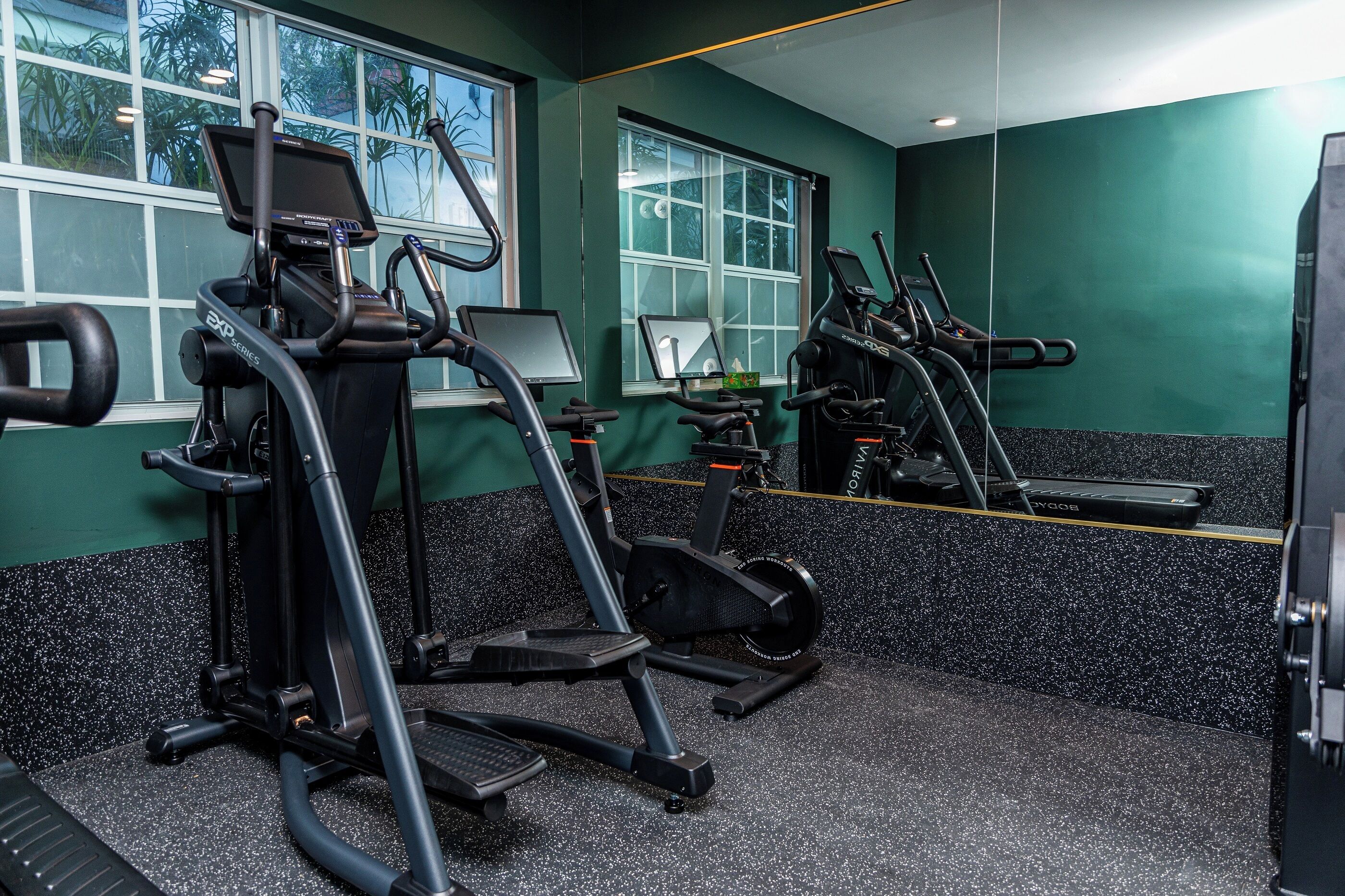 A gym with treadmills, elliptical machines, and a mirrored wall.