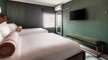 A hotel room with a large bed, a bench, a flat-screen TV, and a window with a view of the outside.