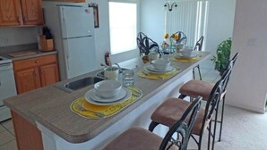 Eine Küche mit Holzausstattung, einem Kühlschrank, einer Spüle und einer Essecke mit Tisch und vier Stühlen.