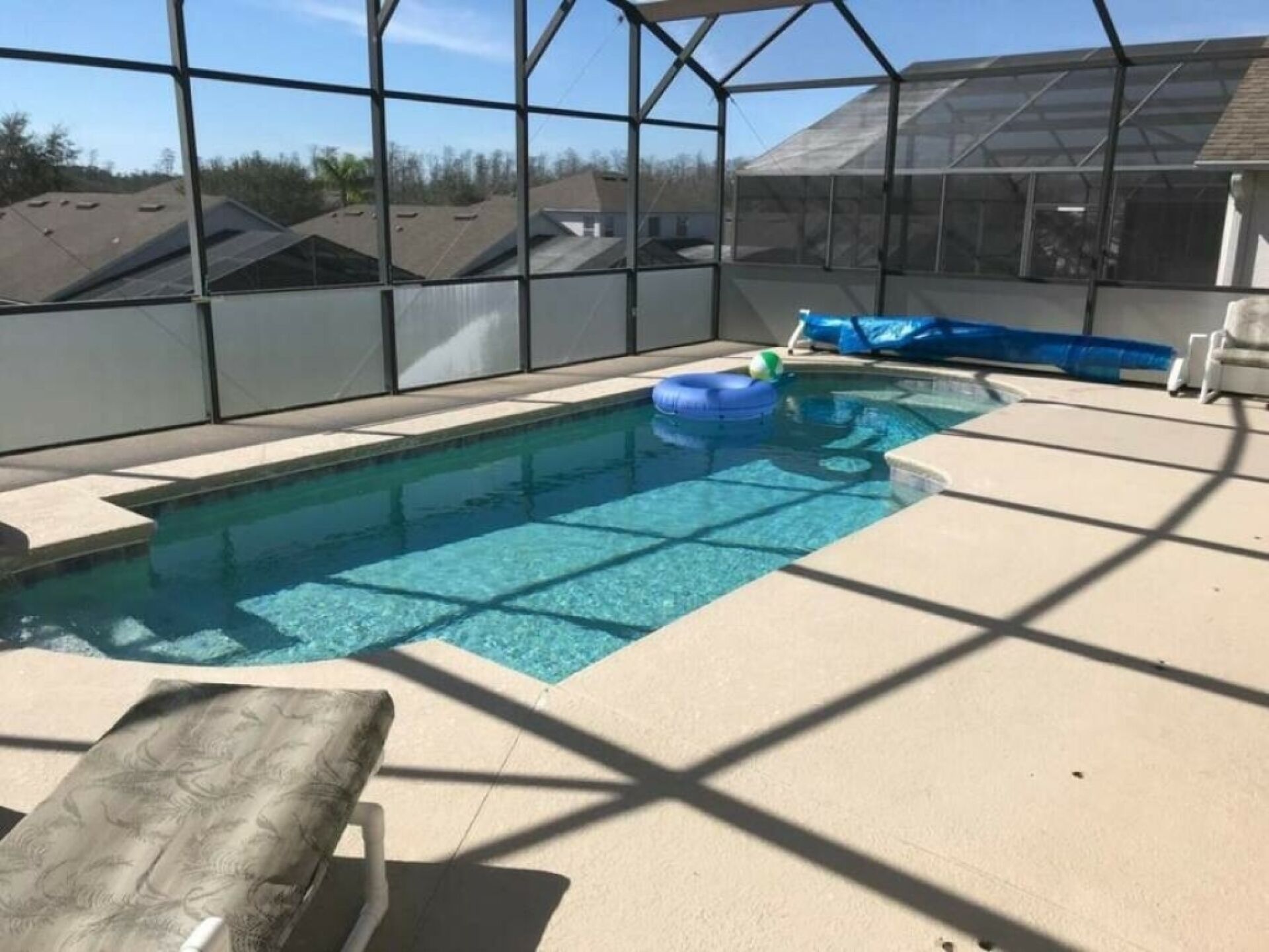 An indoor swimming pool with clear water, a blue inflatable float, and a lounge chair.
