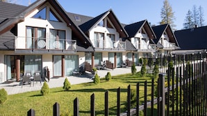 A row of modern, two-story houses with large windows and balconies, surrounded by a wooden fence and a well-maintained lawn. - Apartamenty Domki Giewont (Zakopane)