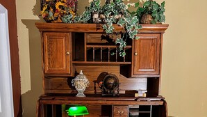 Een houten bureau met meerdere laden en planken, een wereldbol, een lamp en decoratieve planten.