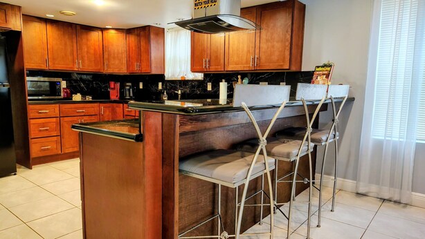 Una cocina con armarios de madera, un microondas y una barra con taburetes.