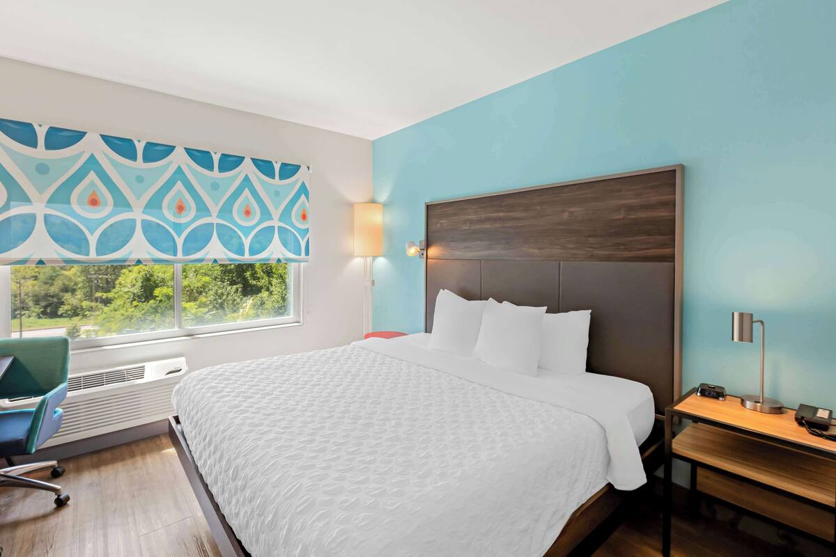Ein modernes Hotelzimmer mit einem großen Bett, einem Schreibtisch und einem Stuhl.