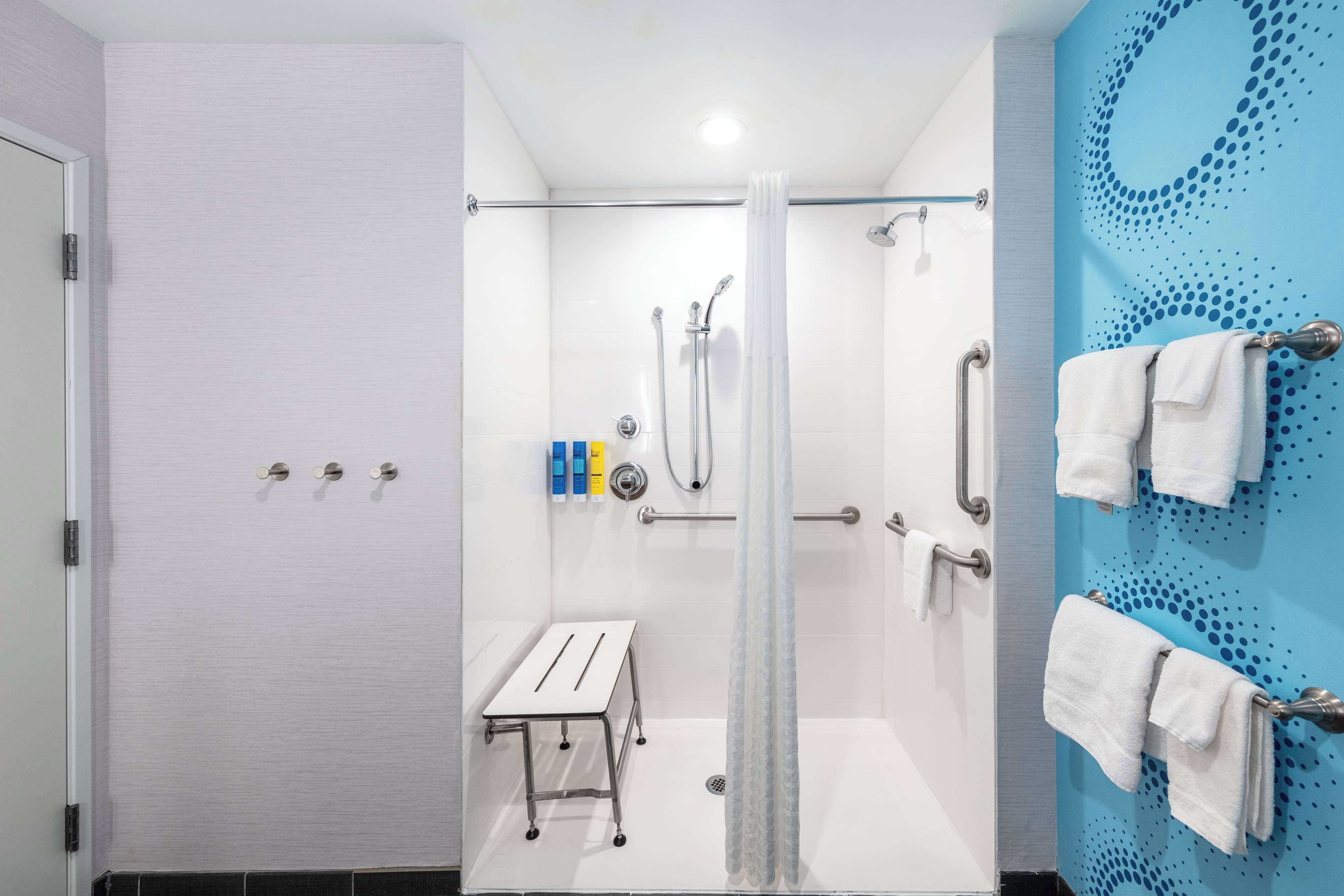 Een moderne badkamer met een douche, een klein tafeltje en een handdoekhouder.