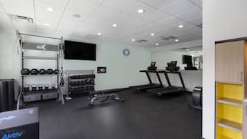 A gym with treadmills, a bench press, and a rack of dumbbells.