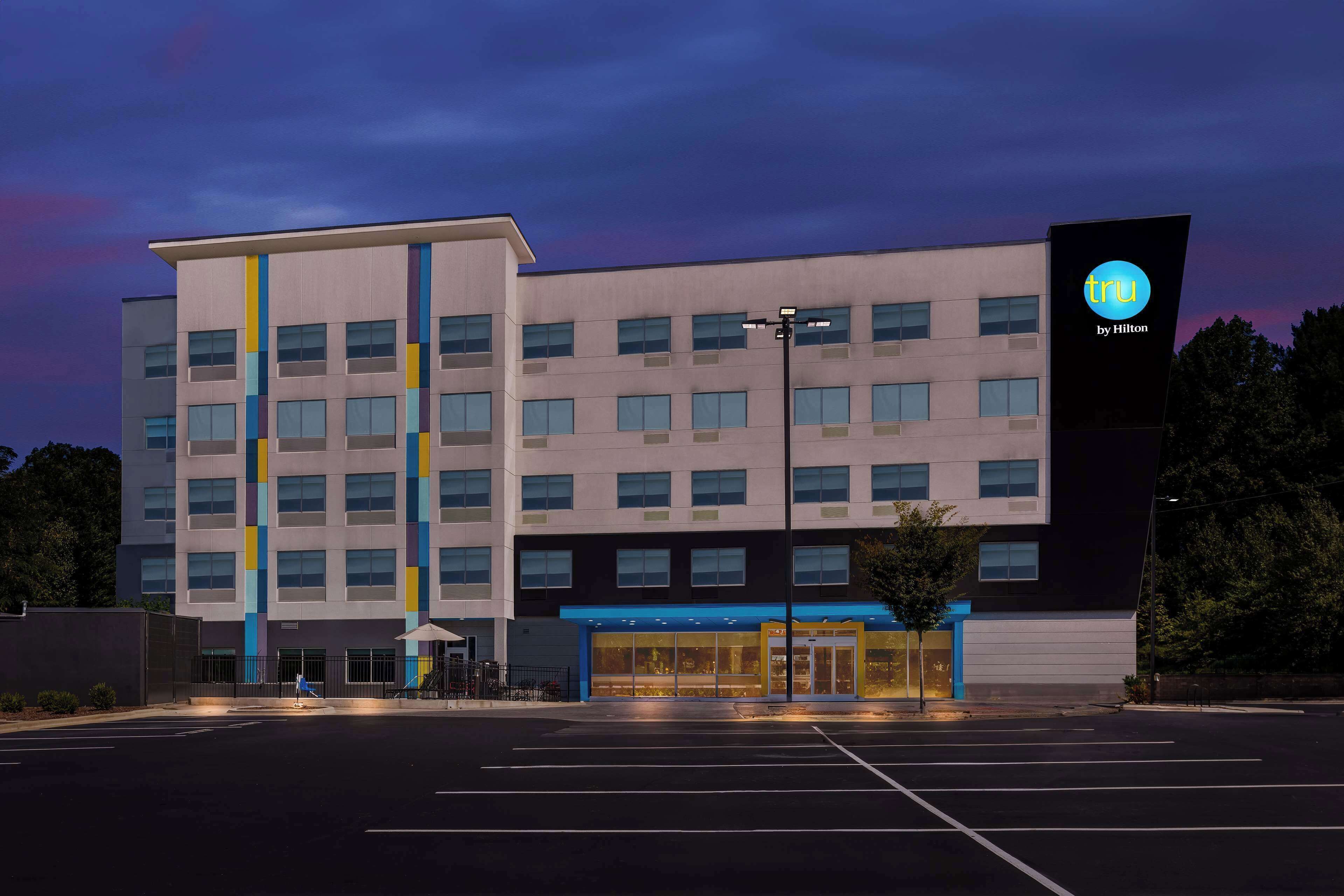 A modern hotel with a multi-story structure, a prominent entrance with glass doors, and a parking lot in front.