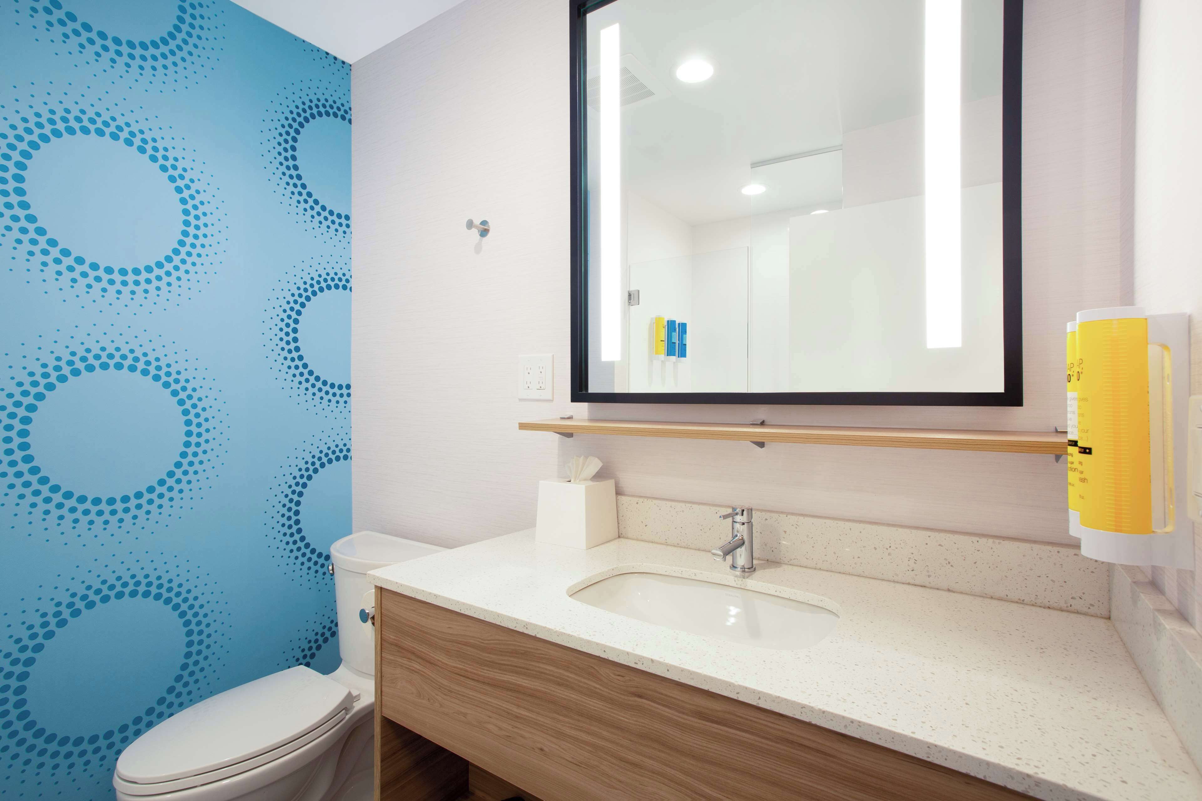 Een badkamer met toilet, wastafel, spiegel en blauw behang.