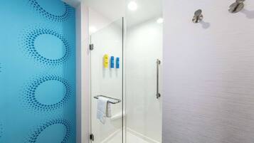 Un baño moderno con cabina de ducha de vidrio, un perchero y artículos de tocador en la pared.