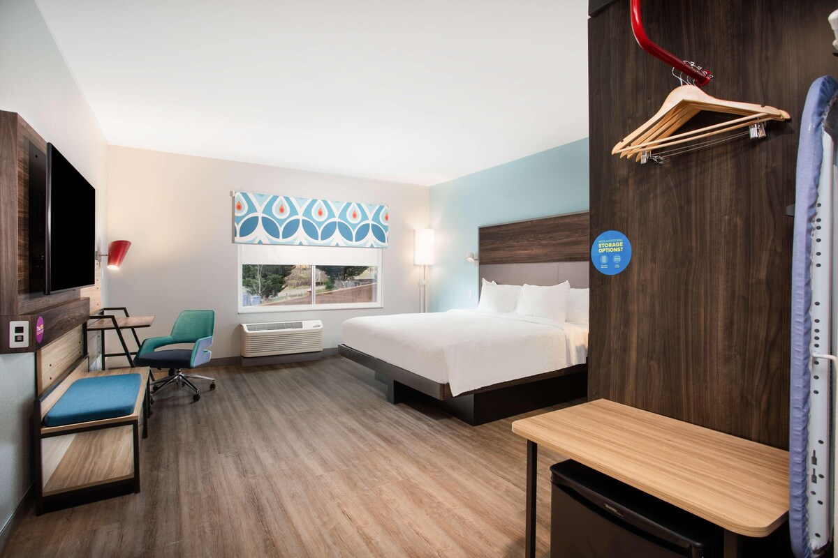 Una habitación de hotel con cama, escritorio, silla, televisor y ventana con vistas.