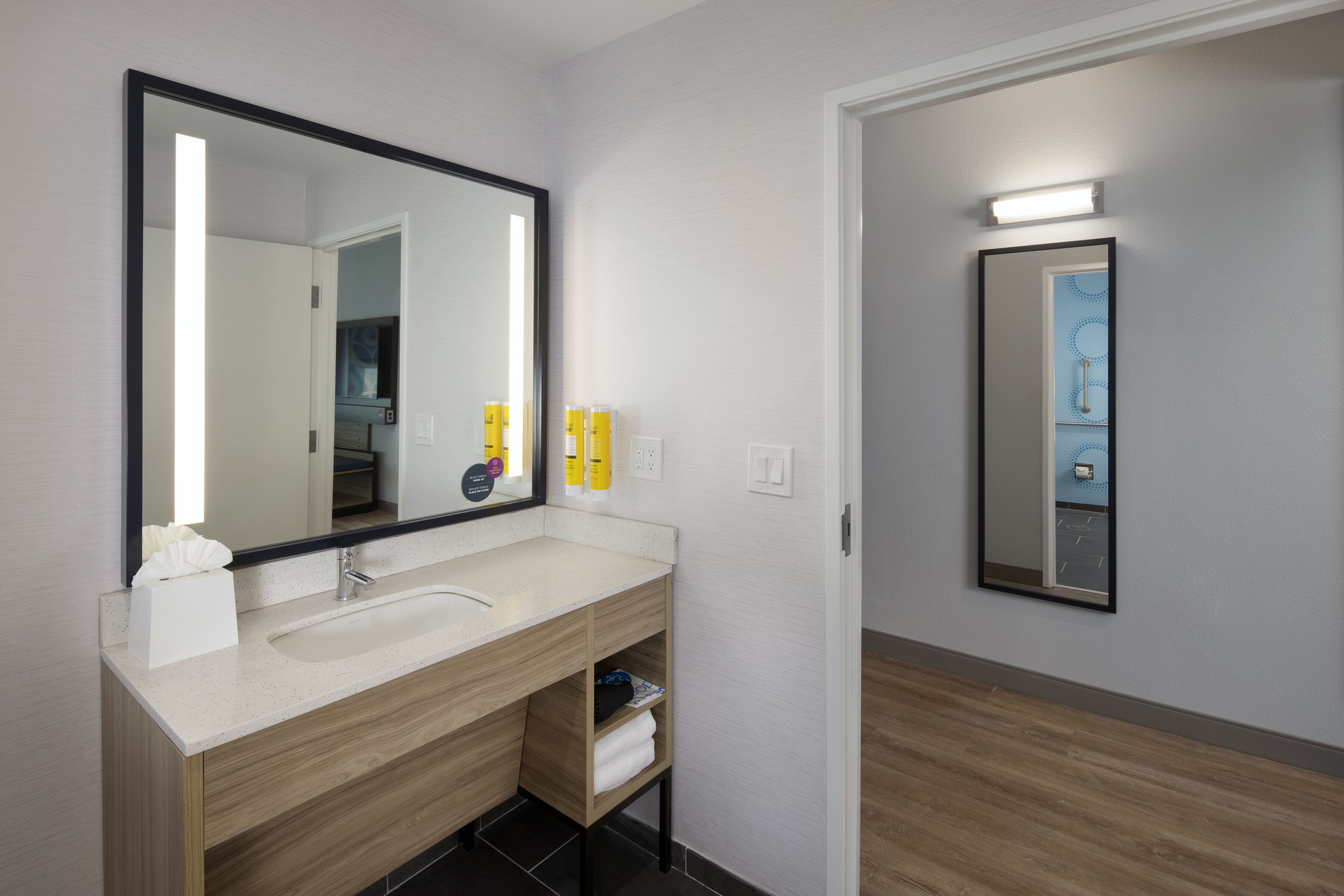 Un baño moderno con un espejo grande, un lavamanos y un mueble de tocador de madera.