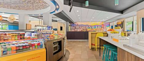 Un interior de cafetería moderno con mostrador, taburetes y una exhibición de bebidas.