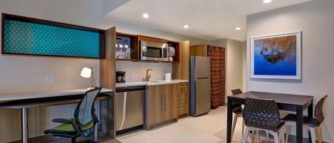 A modern kitchen with stainless steel appliances, a dining area with a table and chairs, and a large window with a view of the city.