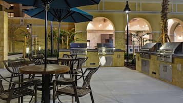 Un patio al aire libre con una mesa redonda y sillas, una estación de parilla y un timbre.