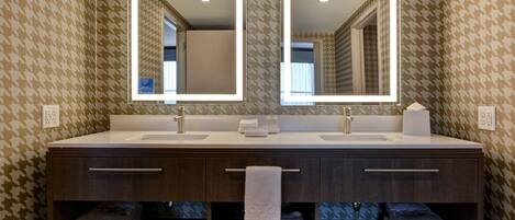 A bathroom with two sinks, a mirror above each, and a towel rack with folded towels.