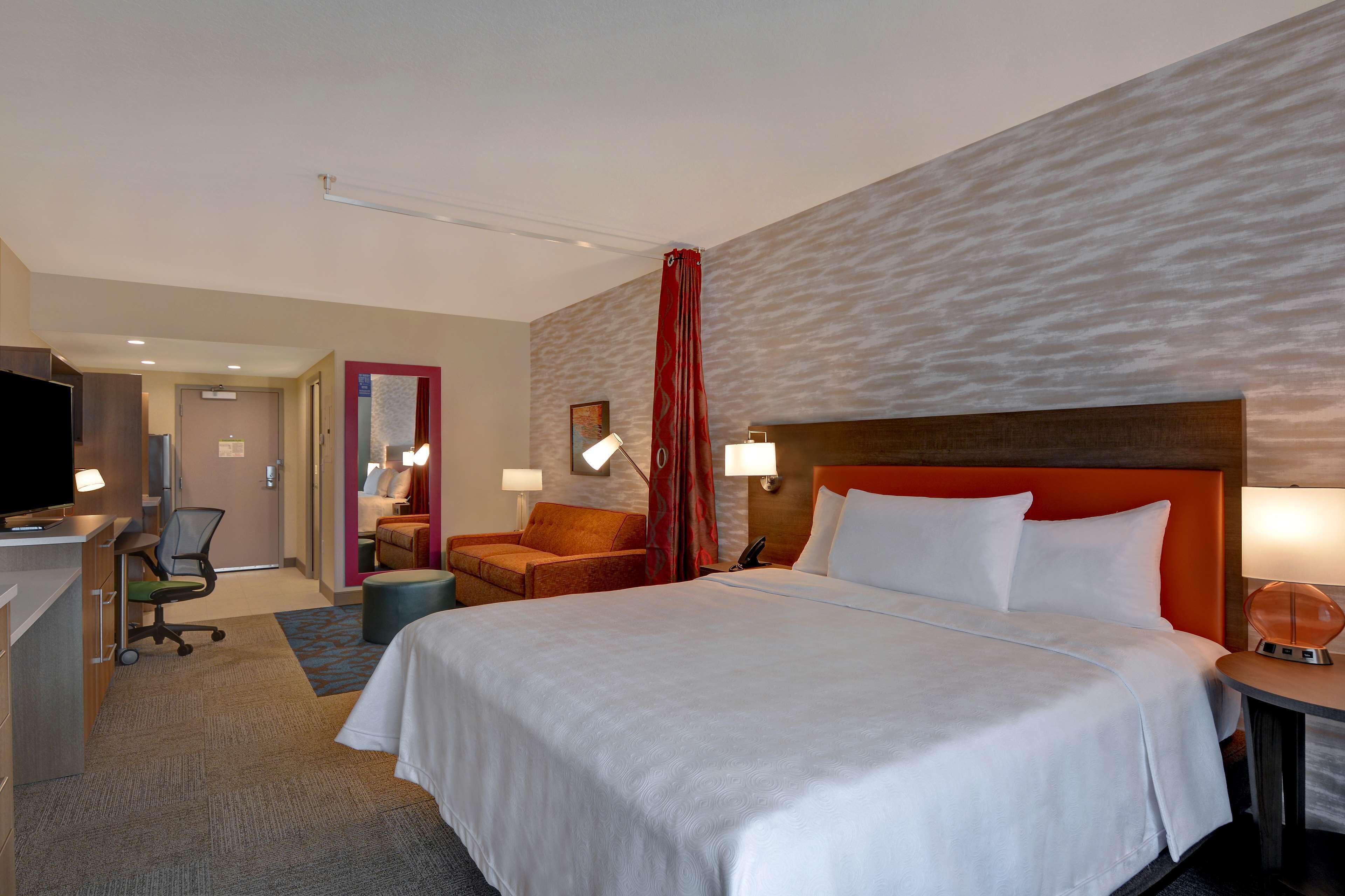 Una habitación de hotel con una cama grande, un escritorio con computadora, una silla y un televisor.