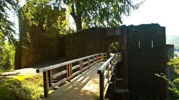 A wooden bridge with a railing leading to a stone structure.