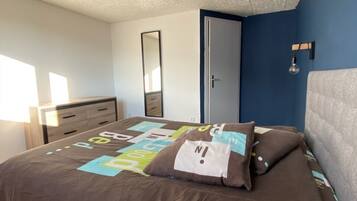 Ein Schlafzimmer mit Bett, Kommode, Spiegel und Tür.