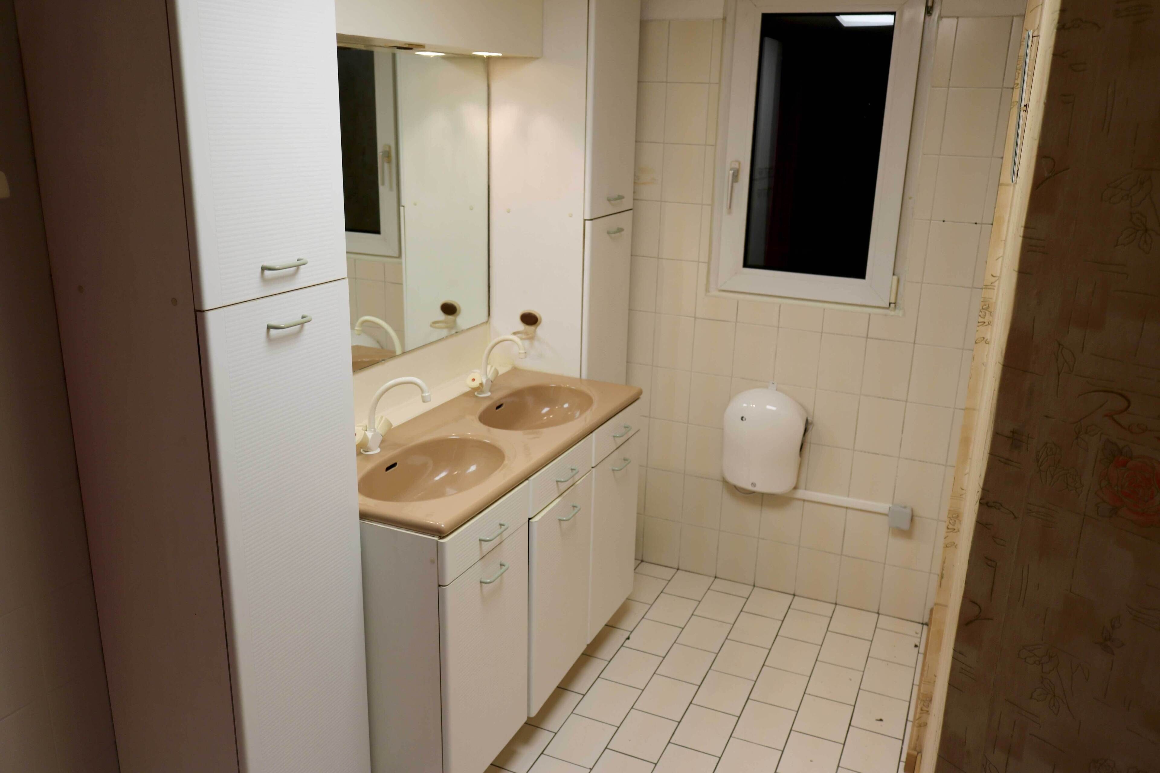 A bathroom with two sinks, a mirror, and a toilet.