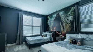 Une chambre avec deux lits, une grande fresque murale et une commode.