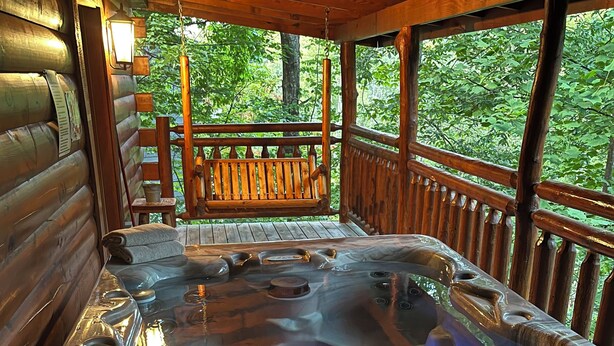 Un jacuzzi en una cabaña de madera con una terraza de madera y un banco.