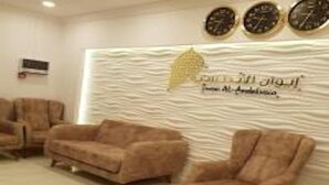 Un espace d’accueil avec un mur à texture, un logo et deux horloges.