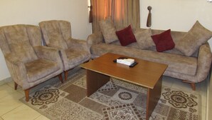 Un salon comprenant un canapé, deux fauteuils, une table basse et un tapis à motifs.