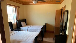 A room with two beds, a ceiling fan, a dresser, and a window with blinds. - Beautiful Bahamas Unit 4 (Nassau)
