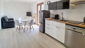 Een moderne keuken met een ingebouwde magnetron, kookplaat en vaatwasser. Er is een eethoek met een tafel en stoelen.