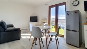 Een moderne woonkamer met een bank, eettafel, stoelen, een flatscreen televisie en een koelkast.