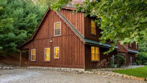 A wooden cabin with a steep gable roof, a front porch, and a gravel driveway. - Blue Spruce . Trailside Lodging (Millersburg)