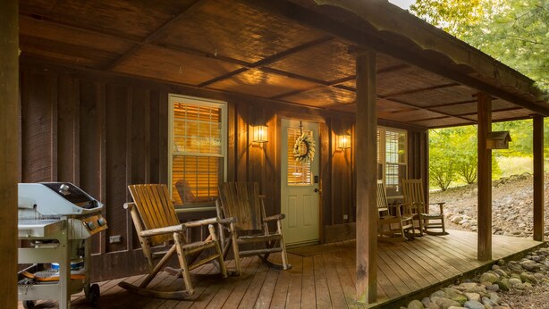 A rustic cabin with a porch, wooden rocking chairs, and a grill. - Blue Spruce . Trailside Lodging (Millersburg)