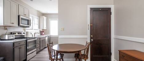 A kitchen with a dining table and chairs, a microwave, a toaster, and a stove.