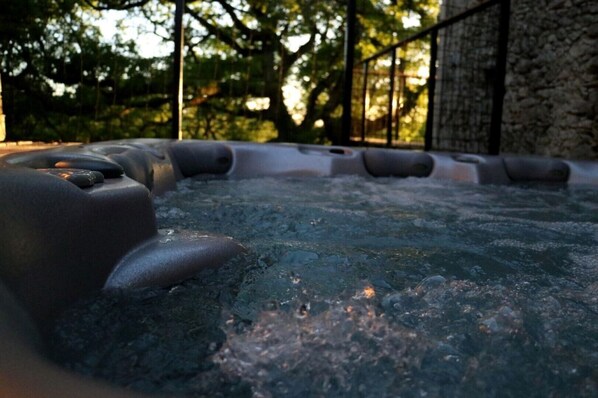 Un jacuzzi con una pared de piedra y árboles al fondo.