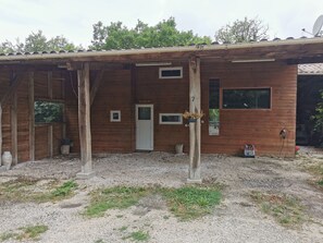 A wooden building with a gravel ground, a door, and a window. - Gîte 2 to 10 travellers + private SPA + swimming pool in season (brassac)