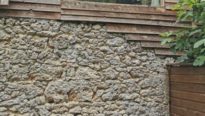A rustic building with a stone wall, wooden siding, and a window.