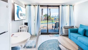 Een moderne hotelkamer met balkon, zwembadzicht, een eethoek en een zithoek.