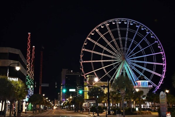 A nighttime cityscape with a large Ferris wheel and a brightly lit tower. - First Floor,Direct Oceanfront,Beautiful Decor,Nice (Myrtle Beach)
