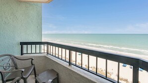 Un balcon avec vue sur la plage, une chaise et une petite table.