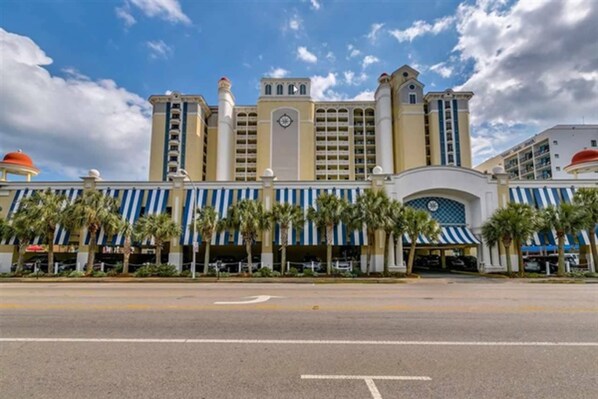 A large hotel with multiple floors, a central clock tower, and a blue and white striped facade.