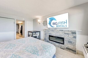 A bedroom with a large bed, a fireplace, a television, and a sign for Big Fish Rentals.