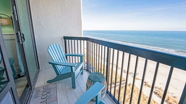 A balcony with two Adirondack chairs, a wicker chair, and a view of the ocean. - Amazing  Beachfront Views, Decorated and Renovated (Myrtle Beach)
