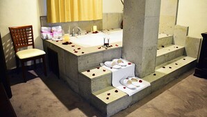 Une salle de bain avec une grande baignoire, une chaise et un lavabo décoré de pétales de rose.