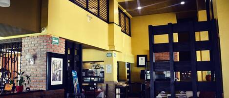 Un restaurant situé à l’intérieur, avec des murs en briques, des murs peints en jaune et des meubles en bois.
