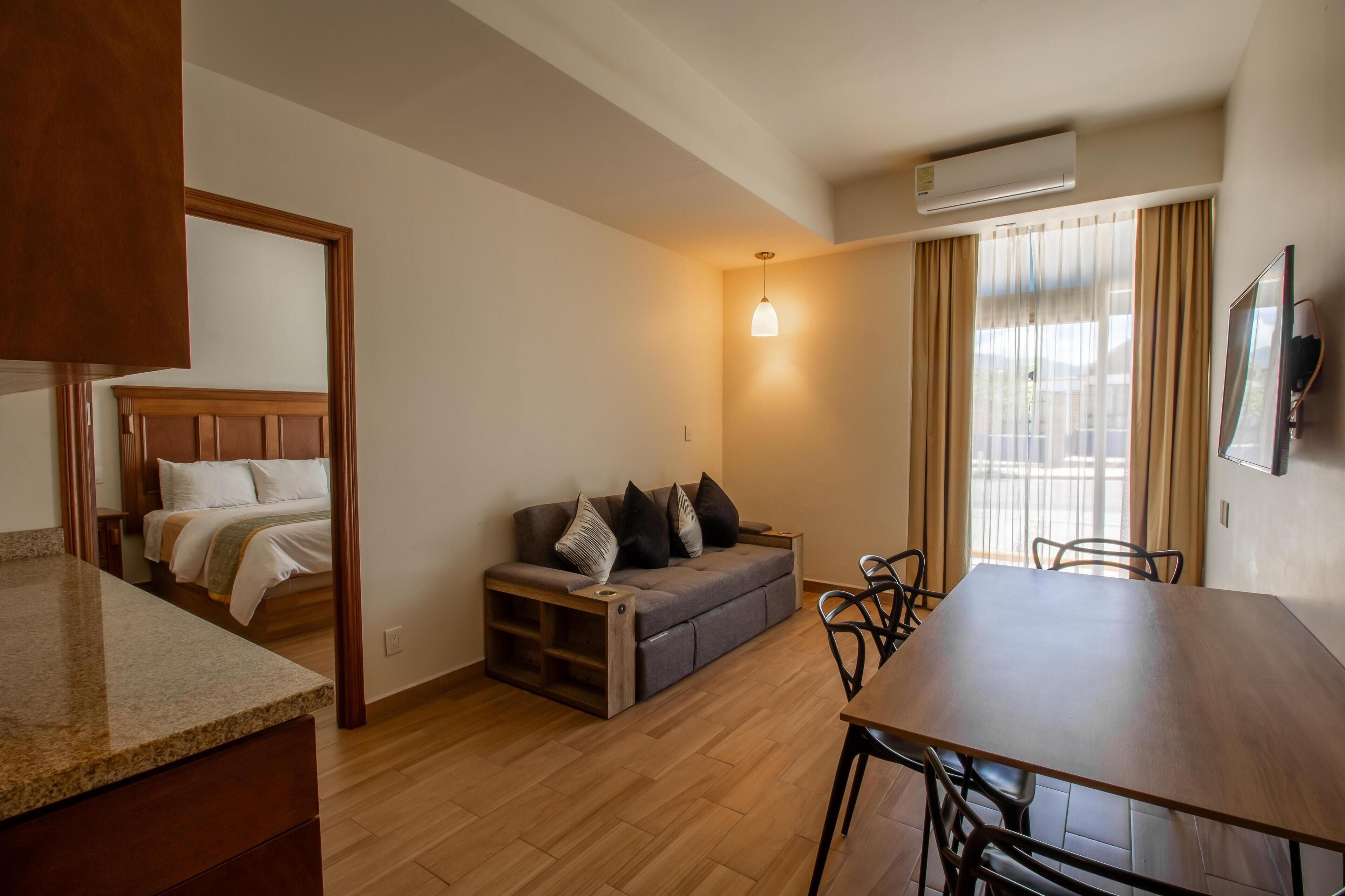 Una habitación de hotel con cama, sofá, mesa de comedor y televisor.