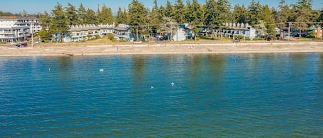 A waterfront property with multiple buildings, a sandy beach, and a calm body of water.