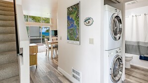 A laundry room with a washing machine and dryer, a map on the wall, and a view of the ocean through a balcony. - JL 202: Lovely water view (Blaine)