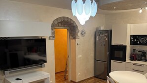 A modern kitchen with a built-in oven, a refrigerator, and a dining area with a white table and chairs. - House with private pool x families and companies (Caprino veronese)